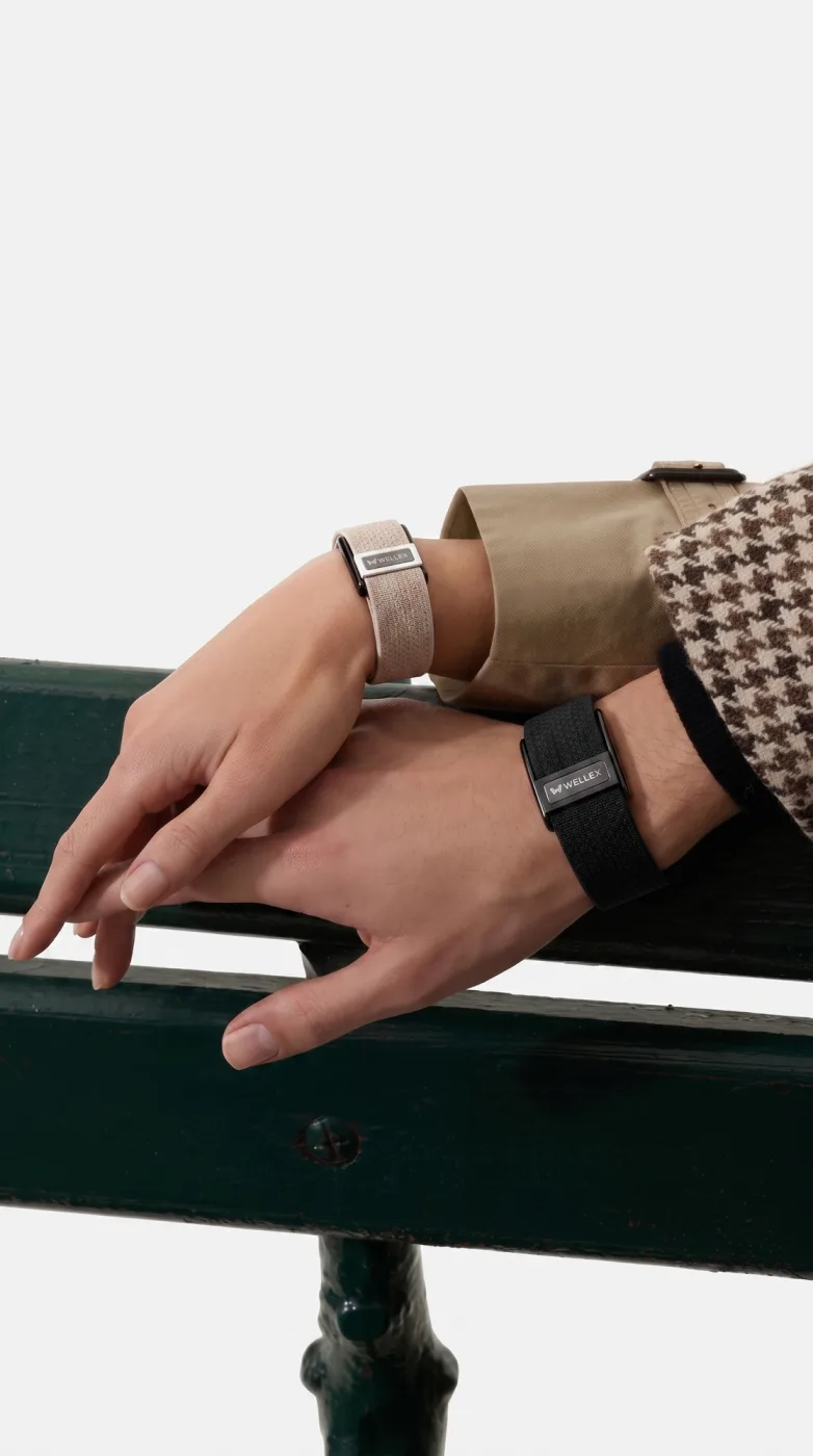 Two people working at the same table, each wearing the band
