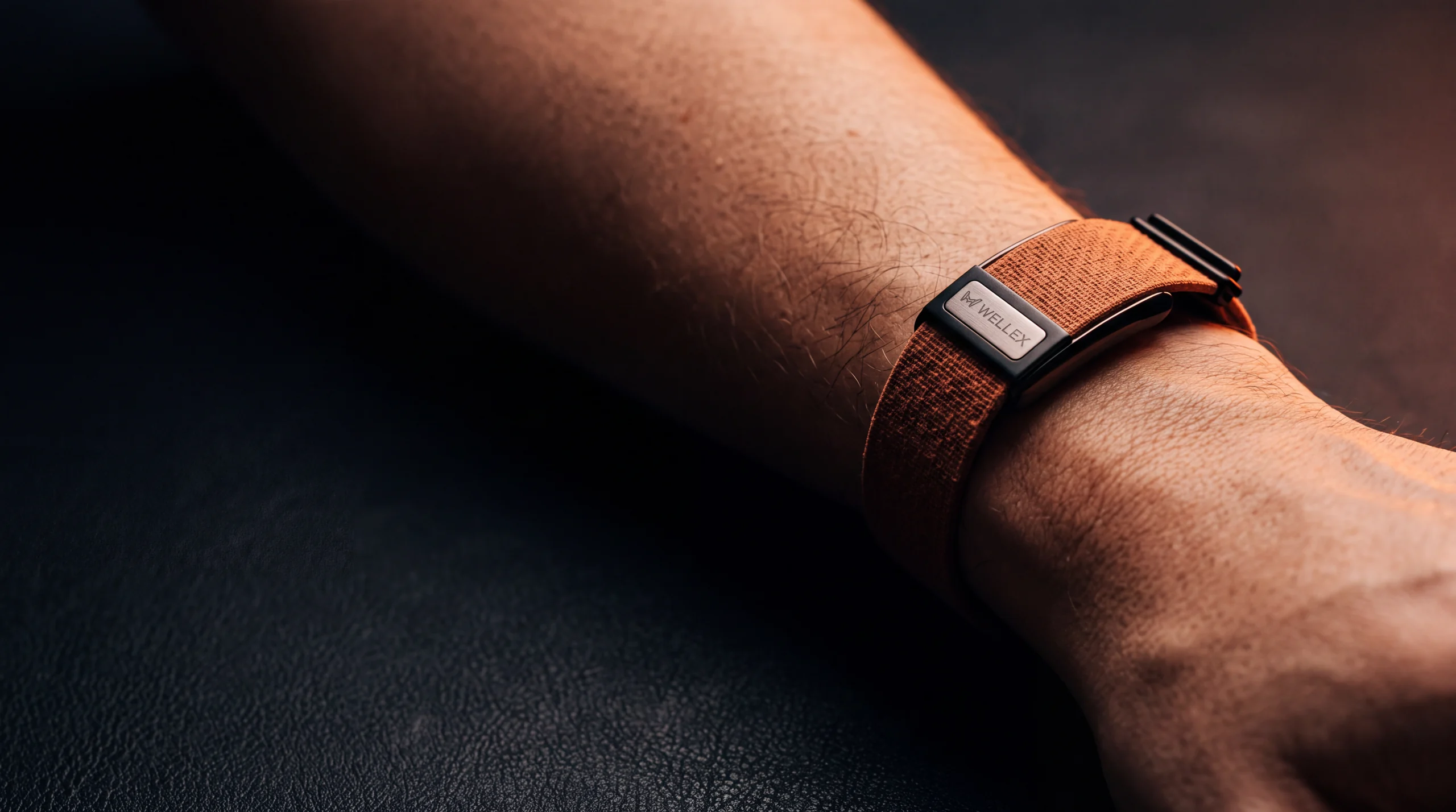 A Wellex band worn on a forearm in warm rim light